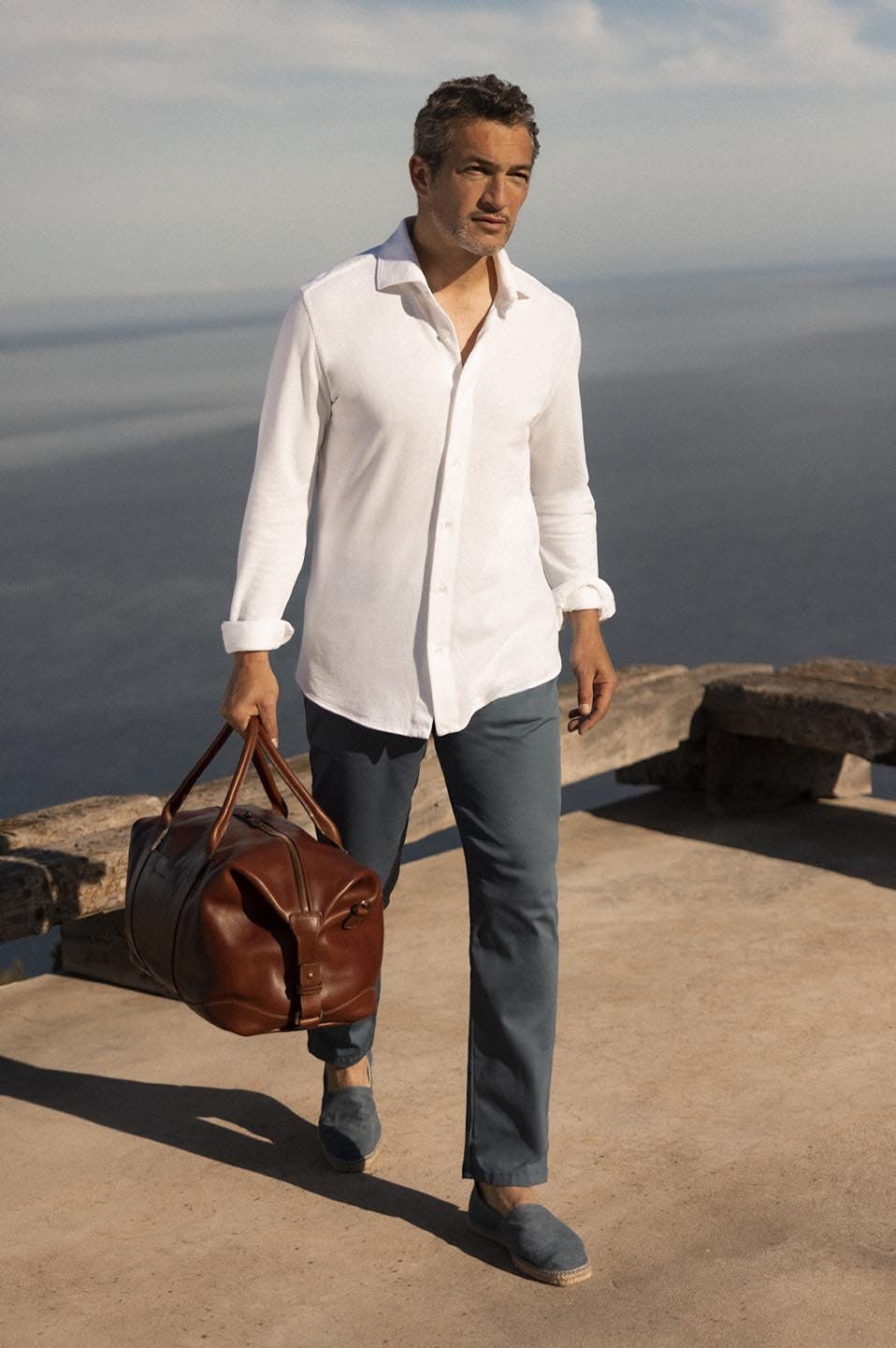 Luca Faloni Model Wearing Cotton Piqué Shirt and Linen Trousers and Leather Weekender Bag